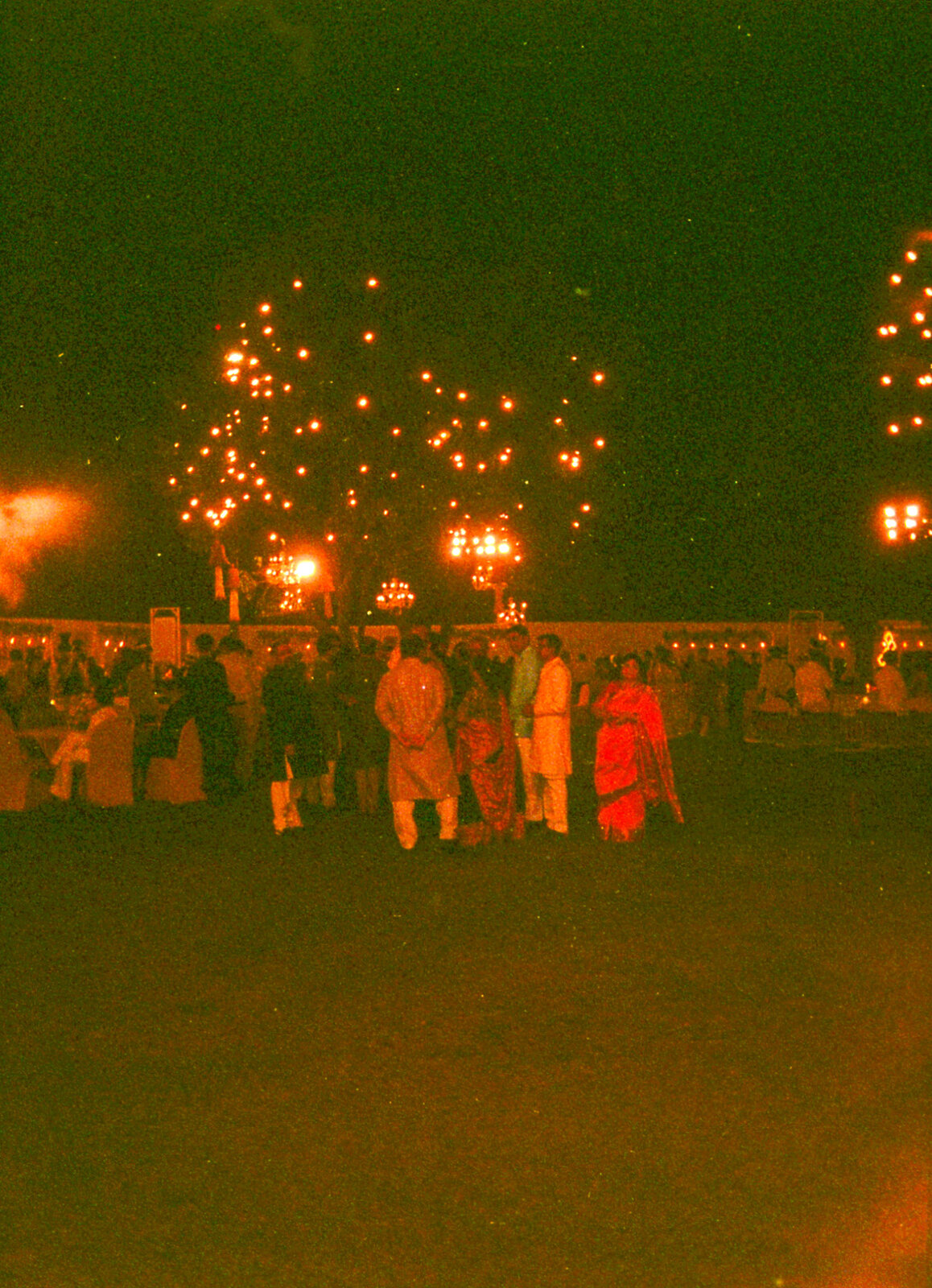 Festival night with strings of lights and a figure in a red sari