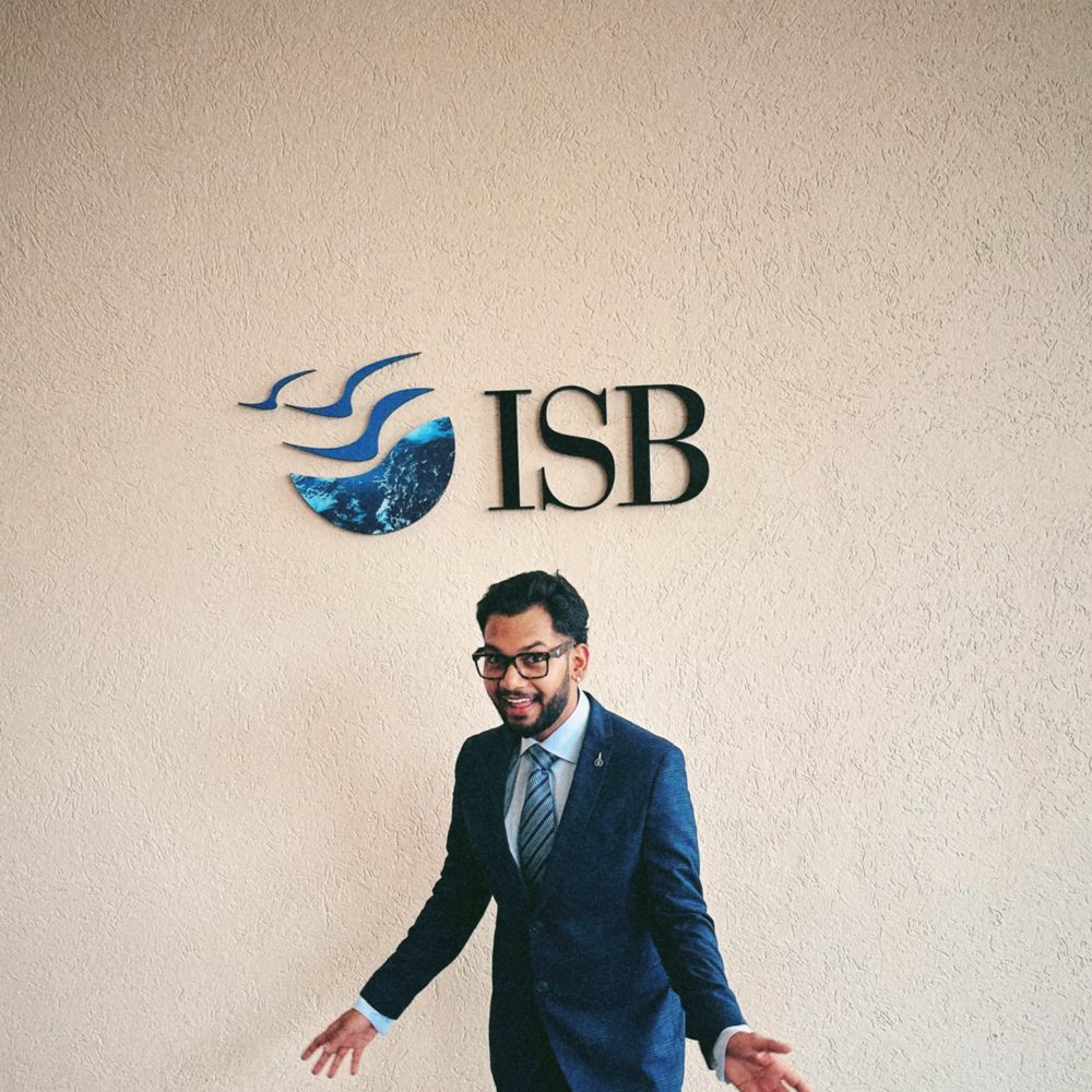 ISB Hyderabad — suited, at the logo wall