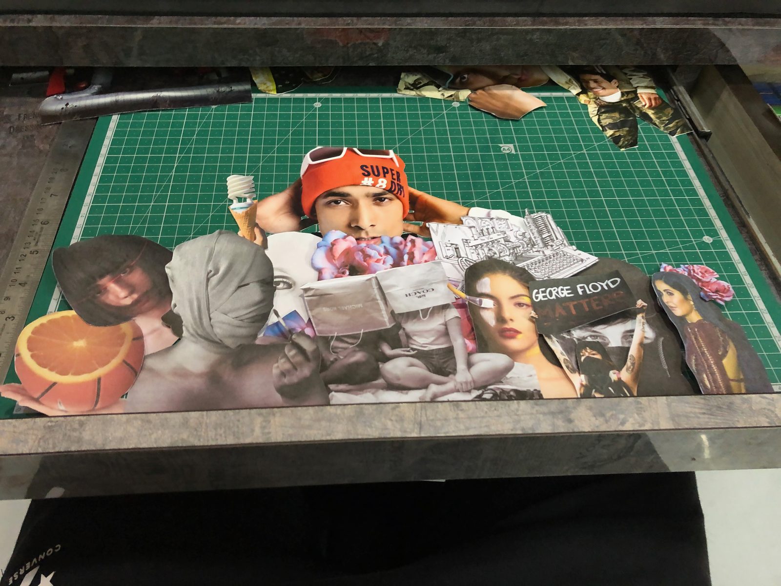 The same collage in progress, laid out on a green self-healing cutting mat with a steel ruler alongside